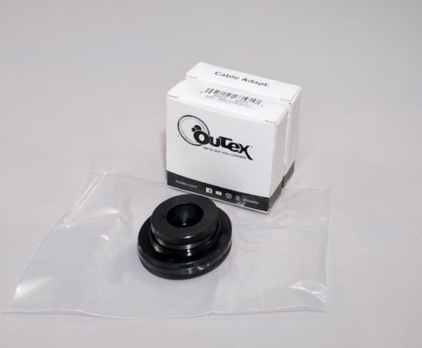 An Outex black camera adaptor in a clear bag and a white Outex box from Accessories Miscellaneous are displayed on a light surface.