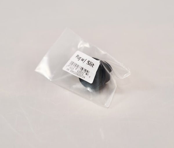 A small black Outex plug with a slit, ideal for tripod adaptors, packaged in clear plastic with a white barcode label: "Accessories Miscellaneous.