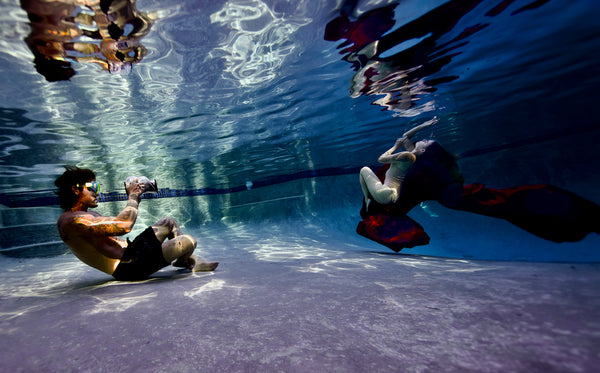Using the Outex Camera Pro Kit, one photographer captures another in a flowing dress underwater in a swimming pool.