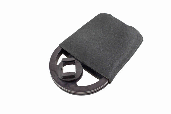A black, oval Outex Maintenance and Care item with a square opening is partly covered by a black fabric strap.