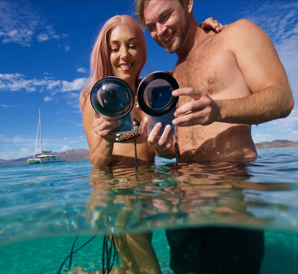 Couple using Outex waterproof smartphone housings while sailing on open water