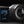 GoPro action camera with a large lens and a small rear display screen, shown on a dark studio background. The GoPro logo is visible on the screen.