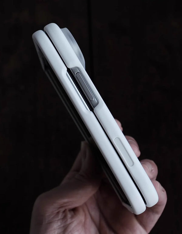 A hand holding the iPhone Due  against a dark, textured background.