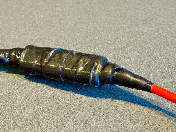Coiled black cable with a red end on a gray surface