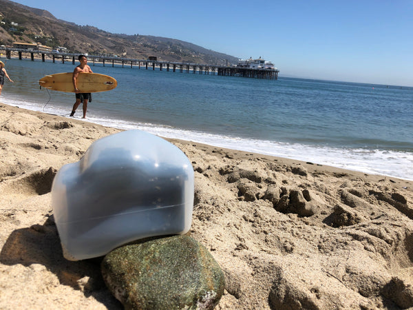 Camera with an Outex case on a beach taking a photo of a surfer