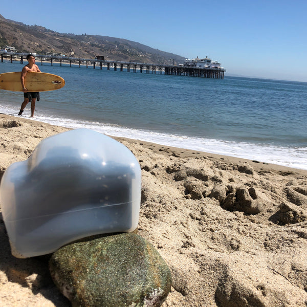 Camera with an Outex case on a beach taking a photo of a surfer