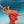 A woman with her arms spread in a red dress is underwater in a pool with blue water