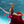 A woman with her arms spread in a red dress is underwater in a pool with blue water
