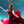 A woman with her arms spread in a red dress is underwater in a pool with blue water